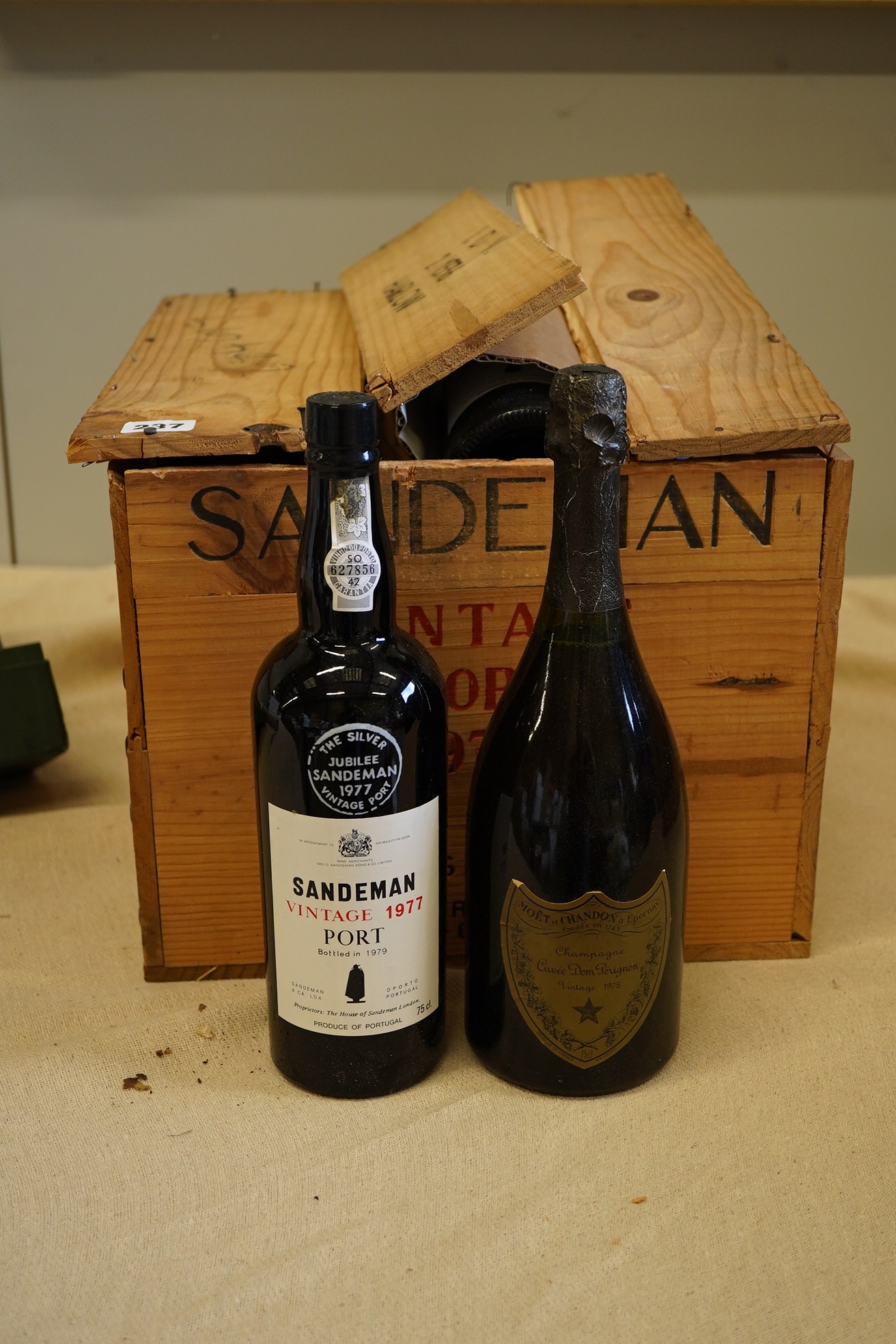 Twelve bottles of 1977 Sandeman vintage port (O.W.C but opened), and a cased bottle of 1978 Dom Perignon champagne